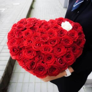 Raudonos rožės širdelės formos gėlių dėžutėje